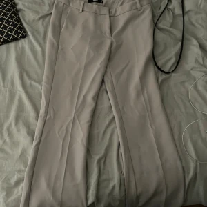 Beiga kostymbyxor från BikBok - Snygga beiga kostymbyxor från BikBok i klassisk rak modell. Byxorna har pressveck, hällor för bälte och diskreta fickor bak. Perfekta för en clean och stilren look. Materialet känns mjukt och har en lätt stretch.