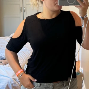 Svart topp med öppna axlar - Svart topp från 157 i storlek S med coola öppna axlar och rund hals. Materialet är mjukt och känns som bomull, perfekt för dig som gillar en enkel men edgy stil. Ärmarna är trekvarts och passformen är normal. Snygg att matcha med jeans eller kjol.