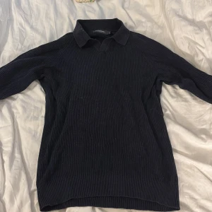 Mörkblå  pikétröja i manchester från Dressmann - Snygg mörkblå  pikétröja från Dressmann i manchester med klassisk krage och lång ärm. Tröjan har en ribbad struktur som ger en cool och stilren look. Perfekt för dig som gillar en lite mer dressad vibe men ändå vill vara bekväm.❤️❤️❤️