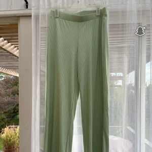 Ljusgröna ribbade byxor från Å - Snygga ljusgröna byxor från Å i ribbat material. Byxorna har raka ben och en mjuk, elastisk midja för extra komfort. Perfekta för dig som gillar en chill och trendig look. Passar till både sneakers och sandaler.