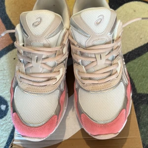 ASICS GEL sneakers i beige och rosa - Snygga ASICS GEL sneakers i beige, rosa och silver med mesh och mockadetaljer. Skorna har rund tå, snörning och coola kontrastpaneler. Perfekta för dig som gillar sportig stil med en twist av färg. Är för liten för mig har haft de i 2 dagar 