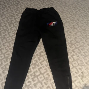 Svarta Trapstar mjukisbyxor  - Svarta mjukisbyxor från Trapstar. Byxorna har smal passform, resår i midjan och dragkedja vid benslut. Perfekta för chill eller streetwear-stil.