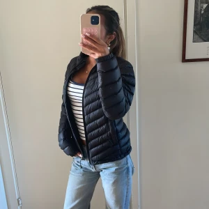 Svart pufferjacka Peak Performance  - Svart pufferjacka från Peak Performance i storlek S. Jackan har quiltad design, hög krage och dragkedja framtill.