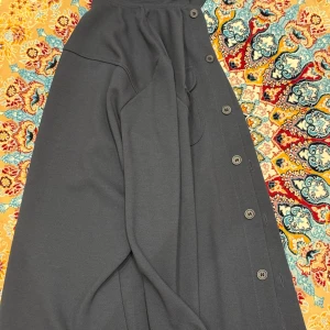 Mörkgrå overshirt med fickor - Snygg mörkgrå overshirt med raka linjer och två stora bröstfickor med knappar. Skjortan har långa ärmar och knäppning hela vägen. 