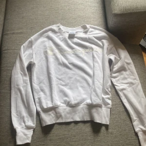 Vit sweatshirt från Champion  - Vit sweatshirt från Champion i storlek XS med klassisk logga i vitt framtill och liten broderad logga på ärmen. Tröjan har rund hals, ribbade muddar och är i ett skönt material