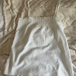 Vit linnetopp med smala axelband - Säljer det här lite som inte kommer till så mycket användning. Vet inte storlek men skulle gissa på s-m. 