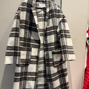 Rutig kappa från Stradivarius - Säljer en oversized rutig kappa från Stradivarius i mjuk ullblandning. Jackan har stora fickor framtill, klassisk krage och går i beige, brunt, vitt och grått.