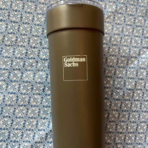 Goldman Sachs Vacuum Insulated Stainless Steel Tumbler - Extremt ovanlig vakuumisolerad termosmugg i rostfritt stål från Goldman Sachs. Håller drycker varma eller kalla länge. Utrustad med tättslutande lock och enkel öppning. Det som ser ut som repor på botten och där fram är klister från tejp och ludd som jag upptäckte efter att jag fotat, tas enkelt bort före frakt.