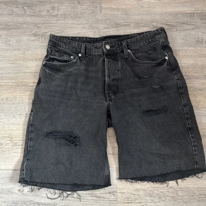 Baggy svarta bermudashorts från H&M - Köpta för 249kr.                 Baggy svarta bermudashorts från &Denim i loose fit med låg midja. Gjorda i bomull med slitna detaljer och råa kanter nertill. Klassisk femficksmodell med knappgylf och coolt, avslappnat uttryck.