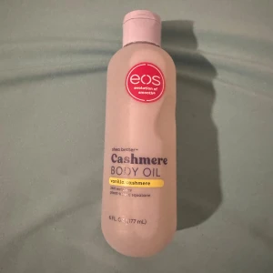EOS Cashmere Body Oil Vanilla - Cashmere Body Oil från EOS med doft av vanilla cashmere. Kommer i en ljusbeige plastflaska med rosa lock och röd logga. Innehåller 177 ml och är berikad med sheasmör och växtbaserad squalane för mjuk och återfuktad hud.