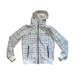 Vit rutig vindjacka - Säljer en vit och grå rutig vindjacka från Wave med huva och hel dragkedja. Jackan har två bröstfickor med knappar och två sidofickor med dragkedja. Mjuka muddar vid ärmslut och nederkant. Perfekt för dig som gillar streetstyle. OBS: Gul stain inuti men syns inte när man väl har på den!