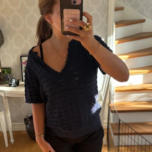 Mörkblå stickad topp med v-ringning - Säljer en mörkblå stickad topp med korta ärmar och v-ringad hals. Tröjan har hål i sig vilket gör att den blir som lite genomskinlig vilket är jätte snyggt. Säljer då den inte kommit till användning då jag har flera liknande tröjor. Knappt använd och inga defekter. Tröjan är från Vila i storlek S
