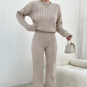 Beige stickade byxor och tröja med kabelmönster - Säljer beige stickat set med snyggt kabelstickat mönster. Byxorna har raka ben och är gjorda i ett mjukt, stickat material som är perfekt för chill dagar. De är både bekväma och trendiga.