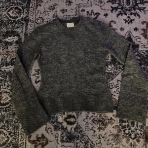 Stickad tröja - Mysig grå stickad tröja från H&M i storlek XS. Tröjan har rund halsringning, ribbade muddar och är långärmad. Perfekt för lager-på-lager och chill dagar.