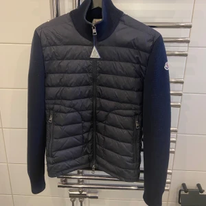 Moncler Cardigan - Säljer denna skitsnygga moncler cardigan i storlek S och färgen navy och jag säljer den eftersom den är för liten på mig.Den är såklart äkta och som ni ser på industri tagen så kan man legit checka.Den är perfekta till nu till våren och den är anpassad till alla årstider speciellt för våren och hösten. Man kan även ha den på milda vinter dagar och kalla sommar dagar. Denna Cardigan är perfekt till dig som letar efter en cardigan i storlek S och passar även Xs och XXs. ❗️pris går att diskutera❗️