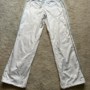 Vita adidas track pants  - Snygga och sköna byxor som inte kommer till användning längre. - silvriga ränder på sidan av benen - medelhöga i midjan - storlek 38, passar även 36 - vida i benen, men går att dra åt längst ner om man vill  Toppenskick, skriv om ni har frågor💓 