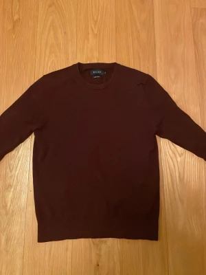 Vinröd merinoullströja från Riley - Snygg vinröd stickad tröja från Riley i mjuk merinoull. Klassisk rund halsringning och långärmad modell som passar perfekt till lager på lager. Enkel och stilren design som funkar till det mesta.Den är 100% merino ull