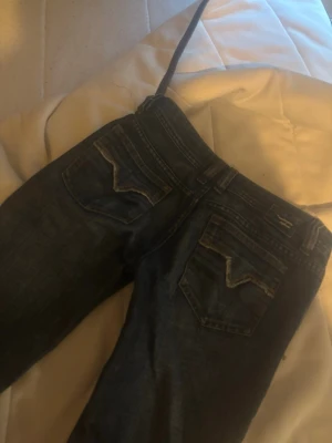 Replay blå jeans med raka ben - Snygga blå jeans från disel med klassiska fem fickor och bootcut. Jeansen har slitna detaljer och tydliga sömmar på bakfickorna. Perfekta för en avslappnad och trendig look.