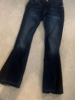 Mörkblå lågmidjade bootcut jeans  - Mörkblåa låg midjade bootcut jeans som egentligen var skinni jeans, men jag har sytt dit en svart tygbit så att de har blivit bootcut. 