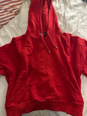 Röd hoodie med huva och ficka - Snygg röd hoodie från monki med stor huva och dragsko. Klassisk känguruficka framtill och ribbade muddar vid ärmslut och nederkant. Perfekt för en chill och avslappnad stil. Storlek M men jag tycker mer det känns som en S.