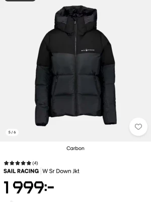 Svart dunjacka från Sail Racing - Snygg svart dunjacka från Sail Racing med hög krage och huva. Jackan har quiltad design, dragkedja framtill och två sidofickor med dragkedja. Perfekt för kalla dagar och har en modern, sportig look. Logotyp på bröstet och stilren passform.