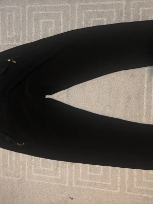 Svarta mjukisbyxor med dragkedjor - Svarta mjukisbyxor med snygga dragkedjor på fickorna. Perfekta för chill dagar eller när du vill ha det bekvämt. Byxorna har en klassisk passform och är gjorda i mjukt material som känns skönt mot huden.