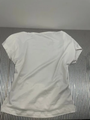 Vit kortärmad topp men öppen rygg - En enkel vit kortärmad topp i mjukt bomullstyg. Modellen har rund halsringning och rak passform, perfekt för en clean och stilren look. Passar till det mesta och är lätt att matcha med andra plagg. Och den har öppen rygg 