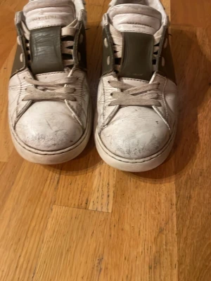 Valentino Open sneakers vit/oliv - Säljer ett par Valentino Open sneakers i vitt skinn med olivgröna detaljer på sidan och tungan. Klassisk rund tå, snörning och platt sula. Ikoniska nitar på sidan ger extra edge. Perfekta för dig som gillar exklusiva och stilrena sneakers. Storlek 40 men passar mig med 41