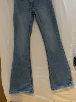 Blå bootcut jeans från Lindex - Snygga blå bootcut jeans från Lindex i modellen Freja. Jeansen har klassisk femficksdesign, normal passform upptill och utsvängda ben. Tillverkade i mjukt bomullsmaterial med en ljus tvätt som ger en avslappnad look.