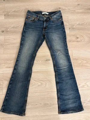 Blå bootcut jeans  - Snygga blå bootcut jeans med klassisk femficksdesign och slitningar på framsidan. Jeansen har normal passform och är tillverkade i ett tåligt denimtyg av bomull. Perfekta för en avslappnad och trendig look.