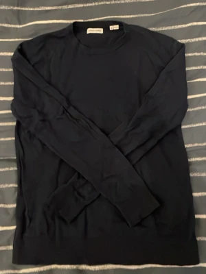 Marinblå från Jack & Jones - En stilren svart tröja från Jack & Jones med rund halsringning och långa ärmar. Tröjan är tunnstickad och har ribbade muddar vid ärmslut och nederkant. Perfekt för lager på lager och enkel att matcha med olika outfits.