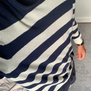 Randig hoodie från Gran Sasso - Snygg hoodie från Gran Sasso i marinblått och vitt med breda ränder. Tröjan har huva, lång ärm och är tillverkad i mjuk stickad bomull. Perfekt för dig som gillar klassisk stil med en twist. Passar dig som vill ha en chill och bekväm look.