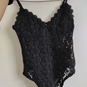 Svart body - En snygg body från hm i storlek 34. Den är i ett spets liknande material som är lite genomskinligt men har dubbelt tyg över brösten så att man inte måste ha bh under.