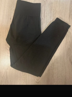 Svarta seamless leggings från Gymshark - Svarta seamless leggings från Gymshark med diskret mönstrad struktur längs benen och hög midja. Stretchigt material som sitter tight och bekvämt. Perfekta för träning eller chill. Liten Gymshark-logga på höften.