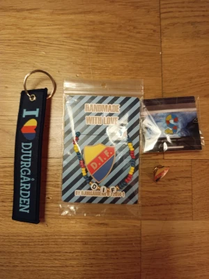 Djurgården smyckespaket supporter - Paket med supporteraccessoarer från Djurgården: nyckelring med texten 'I ❤️ Djurgården', pärlarmband i klubbens färger med DIF-bokstäver,två  pins med klubbsköld. . Perfekt för Djurgården-fans!