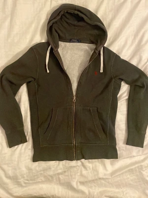 Mörkgrå Ralph lauren hoodie - Riktigt fet och stilren hoodie ifrån polo Ralph lauren. Väldigt stilren och passar till det mesta. Passar som bäst om man är mellan 170-180. 