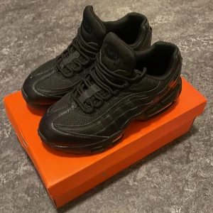 Svarta Nike Air Max sneakers - Snygga helsvarta Nike Air Max sneakers med klassisk siluett och synlig luftdämpning i sulan. Ovandelen är i en mix av mesh och syntetmaterial med tydliga paneler och snörning framtill. Perfekta för dig som gillar en sportig och stilren look.