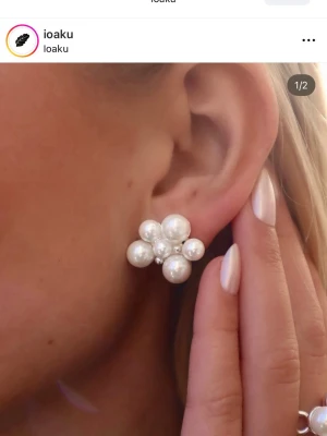 Pärlörhängen från Ioaku - Säljer ett par statementörhängen från Ioaku med flera vita pärlor i olika storlekar samlade i en klusterdesign. Örhängena har en elegant och modern look, perfekta för att lyfta vilken outfit som helst. Materialet är metall och konstpärlor.