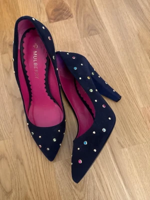 Mulberry Pumps, Navy, suede, 38  - Mulberry Pumps, Navy, suede, 38   Eleganta mörkblå pumps från Mulberry i storlek 38. Skorna har en spetsig tå och är dekorerade med färgade nitar. Perfekt för festliga tillfällen! Använda en gång och är i topp skick.  Titta gärna på mina andra annonser!