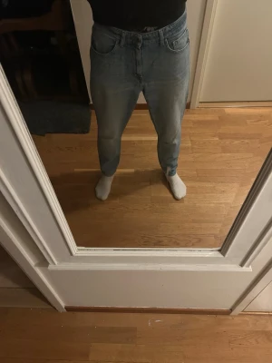 Ljusblå baggy jeans från tiger of Sweden - Säljer ett par ljusblå baggy jeans från tiger of Sweden med klassisk femficksdesign och gylf med dragkedja. Jeansen har en avslappnad passform och raka ben, perfekta för en chill och trendig look. Materialet är mjukt denim i bomull.