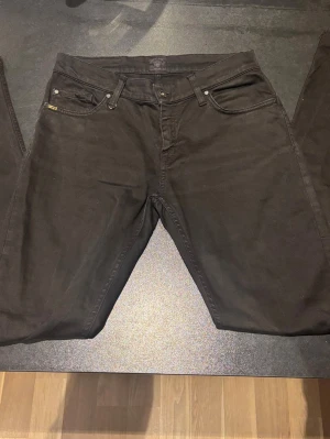 Tiger of Sweden Jeans 29/32 - Snygga svarta jeansbyxor från tiger of Sweden i modellen Elaise. Klassisk femficksdesign med svarta nitar och detaljer, samt en diskret Replay-logga vid fickan. Jeansen har normal passform och är tillverkade i mjukt jeansmaterial. Storlek 29/32