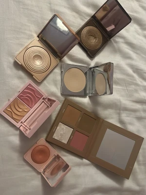 CAIA ansiktspaletter och singelprodukter - Säljer ett gäng CAIA sminkprodukter då jag verkligen inte har ett intresse för smink längre. ansiktspalett med bronzer, rouge och highlighter, singelrouge i persikoton, highlighter i champagne, bronzer i varm brun, puder i ljus beige samt duo med rosa och guldiga nyanser. Alla kommer i snygga metallic- och pastellförpackningar.