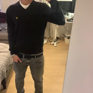 Svart tröja från Lyle & Scott - Säljer en stilren svart tröja från Lyle & Scott med v-ringning och deras ikoniska logga på bröstet. Perfekt för en avslappnad men ändå snygg look. Passar bra till jeans eller chinos. Skriv till mig vid minsta fundering eller fler bilder. Jag är själv 182cm och väger ungefär 65 kg. Det är en L i barnstorlekar vilket motsvarar S i herrstorlekar.