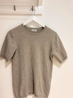 Beige kashmirtröja från Soft Goat - Supermjuk beige kashmirtröja från Soft Goat med korta ärmar och rund hals. Enkel och stilren design som är perfekt för lager-på-lager eller som den är. Tröjan har ribbade muddar vid ärmslut och nederkant.