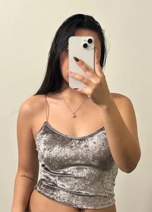 Silvrig sammetslinne med tunna axelband - Säljer en silvrig linnetopp i glansig sammet med tunna, korsade axelband och croppad passform. Toppen har en lätt v-ringad halsringning och öppen rygg. Supersnygg och fint på 🥰