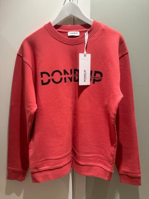 Sweatshirt från Dondup - Helt ny sweatshirt från Dondup med svart logotyptryck framtill. Tröjan har rund halsringning, långa ärmar och är tillverkad i mjuk bomull. Perfekt för dig som gillar en avslappnad och trendig stil. Nypris 1200 kr 