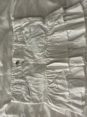 Vit jeansskorts från Gina Tricot - Säljer en vit jeansskorts från Gina Tricot i storlek 152. Men är som xs. Skortsen har klassiska jeansdetaljer med fickor fram och bak, dragkedja och knapp. Den har volangkant med råa, fransiga avslut för en cool look. Perfekt för dig som gillar att sticka ut.