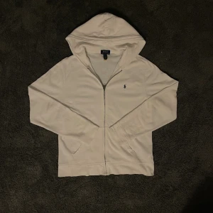 Ralph Lauren Zip up - Riktigt snygg zip från Ralph Lauren. Tröjan är XL i barnstorlek vilket motsvarar S i vuxen storlek. Tröjan har en väldigt liten fläck som visas på sista bilden. Fläcken syns endast på nära håll.  Hör av dig vid frågor.