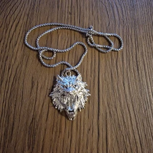 Halsband varg - Halsband med ett stort silverfärgat varghuvud som hänge. 5,5 cm × 4 cm. Inkl kedja. 