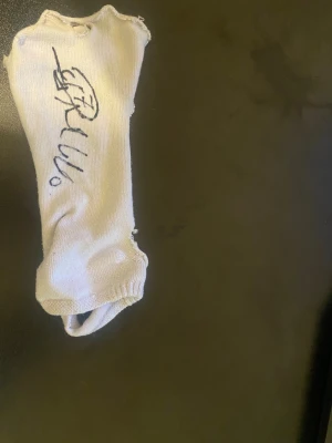 Vit snygg strumpa som Ronaldo har signerat - Unik vit stickad fotväst med handskriven autograf från Cristiano Ronaldo på ovansidan. Strumpan har öppna sidor för foten och elastisk kant runt ankeln. Perfekt för dig som vill ha något annorlunda och kreativt på fötterna. Passar dig som gillar autograferade föremål. DM OM NI VILL KÖPA. SÖDER STADION KOKAR OO AA FÖR EN YANNE 🏟️ 👨‍🍳 